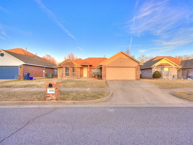 view of front of home with a garage, central AC, brick siding, and driveway