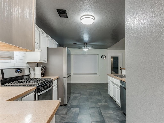 kitchen with light countertops, appliances with stainless steel finishes, decorative backsplash, and white cabinets