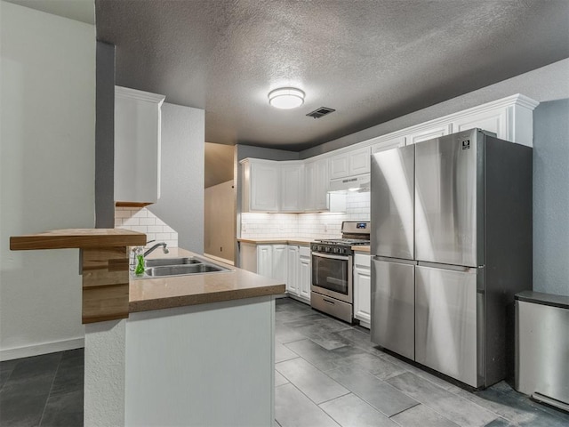 kitchen featuring under cabinet range hood, stainless steel appliances, a peninsula, a sink, and white cabinetry