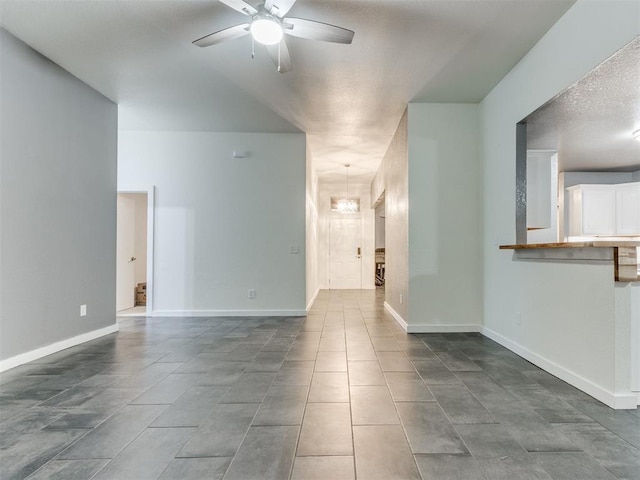 unfurnished living room with dark tile patterned floors, baseboards, and a ceiling fan