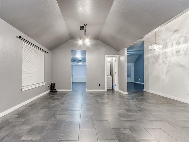 empty room featuring lofted ceiling, a textured ceiling, ceiling fan with notable chandelier, visible vents, and baseboards