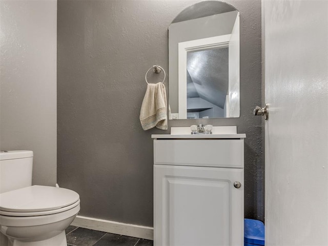 bathroom featuring a textured wall, toilet, vanity, tile patterned flooring, and baseboards