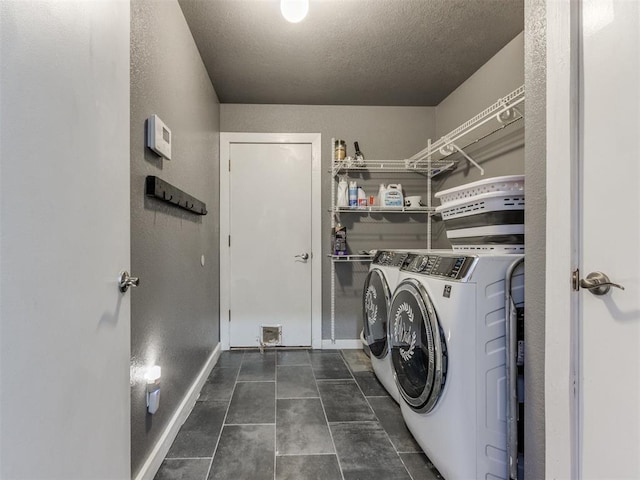 laundry area featuring laundry area, baseboards, a textured ceiling, dark tile patterned floors, and separate washer and dryer