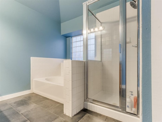 bathroom featuring a garden tub, a shower stall, and baseboards