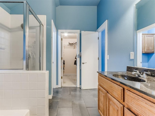 bathroom featuring tile patterned floors, a spacious closet, a shower stall, and vanity