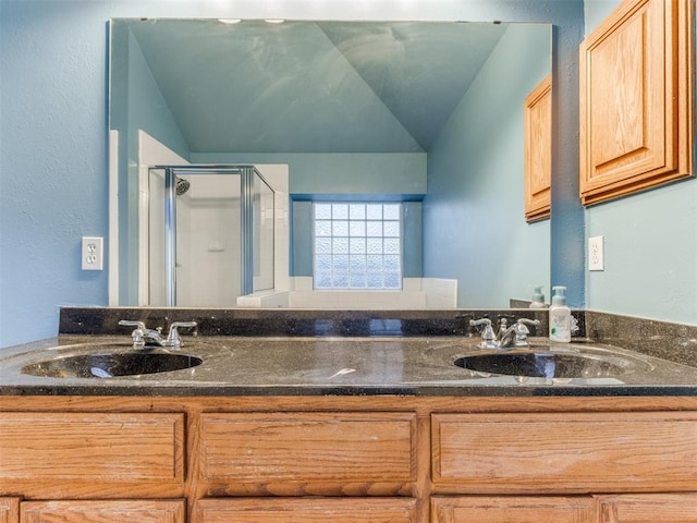 bathroom featuring lofted ceiling, double vanity, a stall shower, and a sink