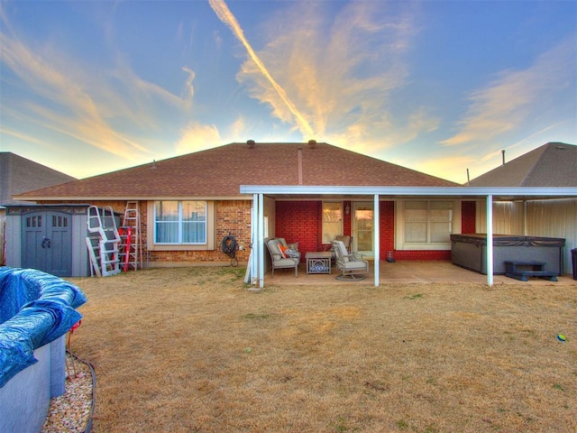 rear view of property featuring an outbuilding, brick siding, a patio, a hot tub, and a storage shed