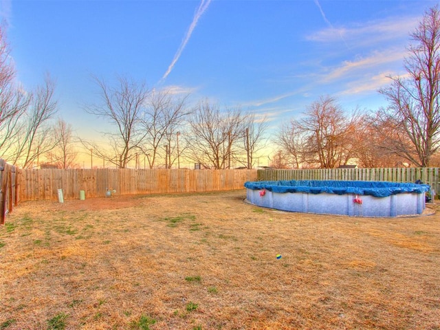 yard at dusk featuring a fenced backyard and a fenced in pool