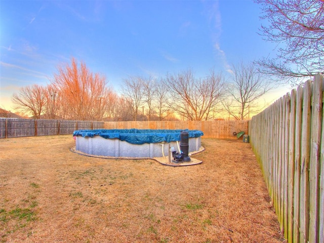 yard at dusk featuring a fenced backyard and a fenced in pool