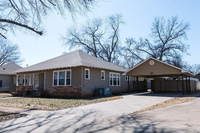 view of property exterior with a carport, stone siding, roof with shingles, and driveway