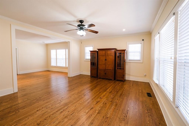 interior space with a healthy amount of sunlight, baseboards, dark wood-style flooring, and crown molding