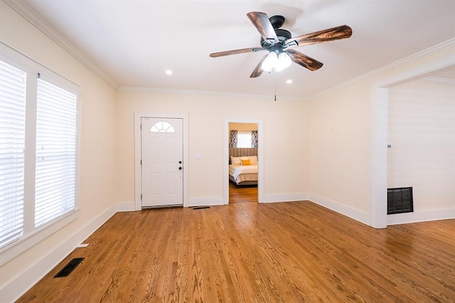 entrance foyer featuring ornamental molding, visible vents, light wood-style floors, and baseboards