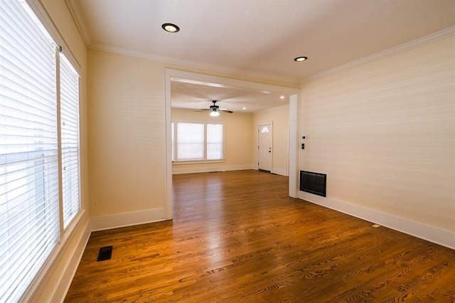 empty room with visible vents, baseboards, ornamental molding, dark wood-style floors, and a glass covered fireplace