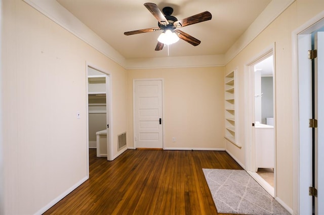 empty room featuring a ceiling fan, dark wood-style flooring, visible vents, and baseboards