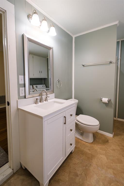 bathroom featuring crown molding, toilet, vanity, and washing machine and clothes dryer