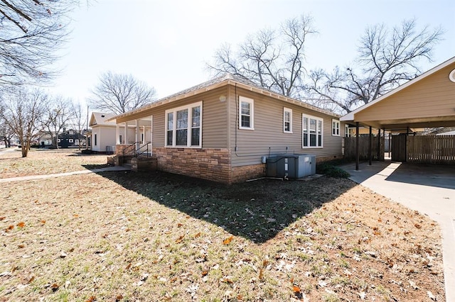 view of side of property with a carport, stone siding, and central AC unit