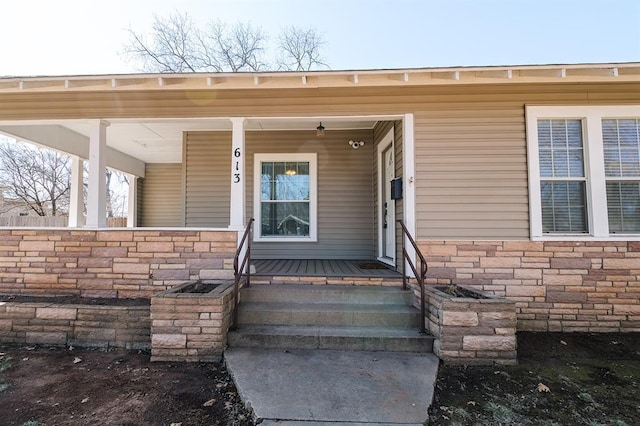 view of exterior entry featuring a porch and stone siding