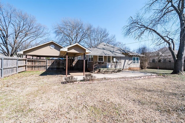 rear view of house featuring fence private yard, a patio area, driveway, and roof with shingles