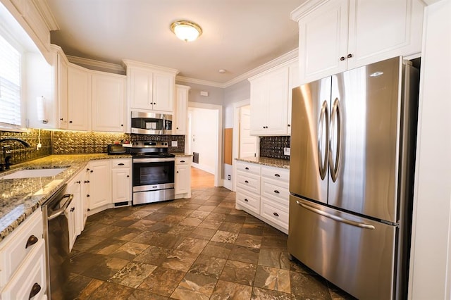 kitchen with crown molding, stainless steel appliances, stone countertops, white cabinetry, and a sink