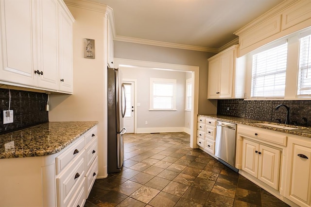 kitchen featuring dark stone counters, stainless steel appliances, tasteful backsplash, and a sink