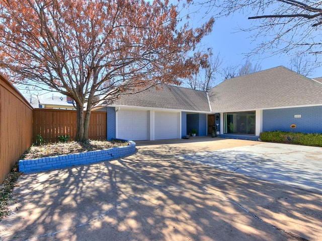 ranch-style house featuring fence, driveway, roof with shingles, an attached garage, and brick siding