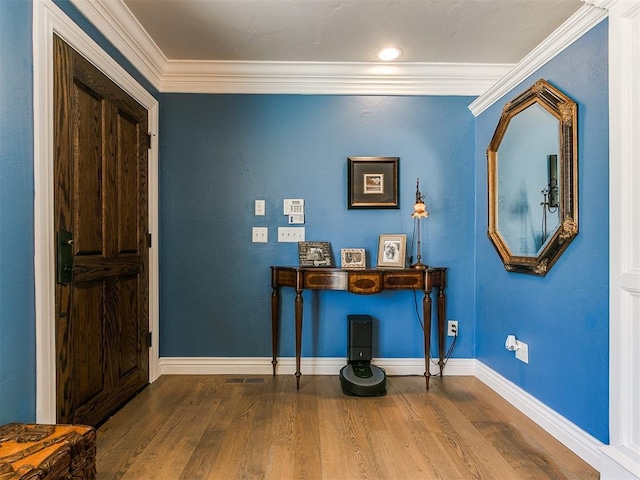 entryway featuring wood finished floors, baseboards, and ornamental molding