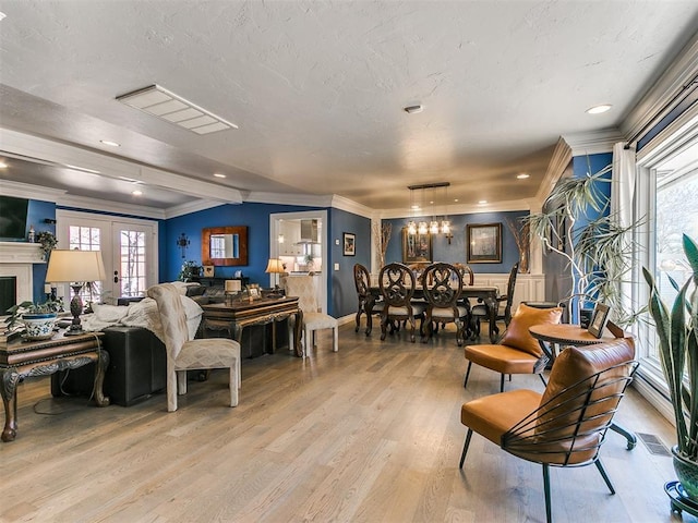 living room with light wood-type flooring, french doors, a textured ceiling, and crown molding