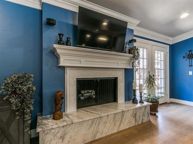 living room featuring a premium fireplace, wood finished floors, baseboards, and ornamental molding