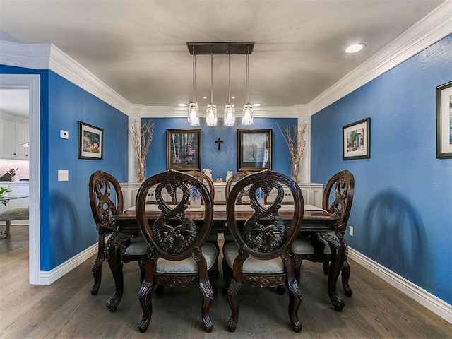 dining room with wood finished floors, crown molding, and decorative columns