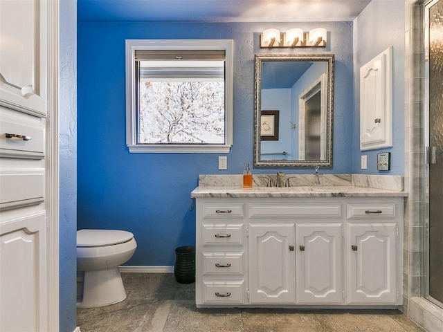 bathroom featuring vanity, a shower with shower door, toilet, and baseboards