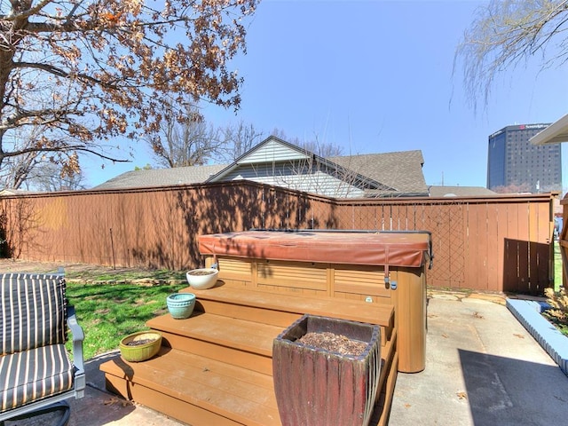 view of patio / terrace with a covered hot tub and fence