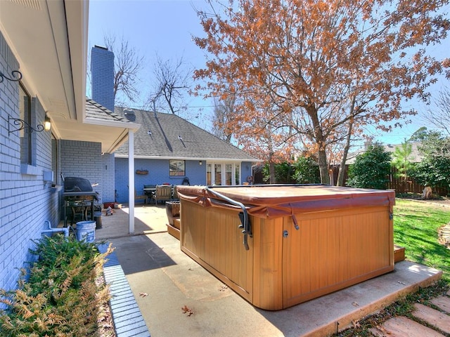 view of patio featuring area for grilling, fence, and a hot tub