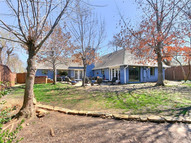 rear view of property featuring a fenced backyard, french doors, a patio area, brick siding, and a hot tub