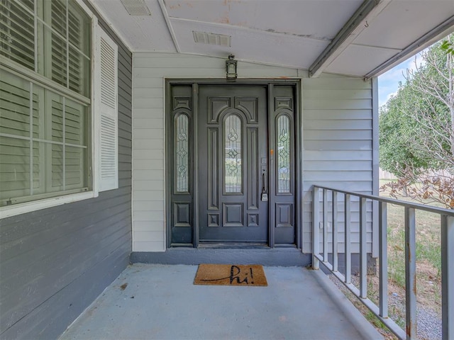 property entrance featuring covered porch and visible vents