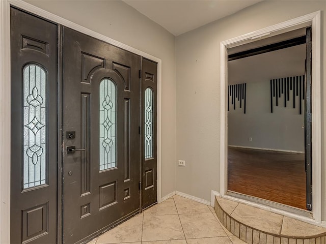 foyer entrance with baseboards and light tile patterned floors