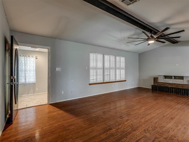 unfurnished living room with vaulted ceiling with beams, plenty of natural light, and wood finished floors