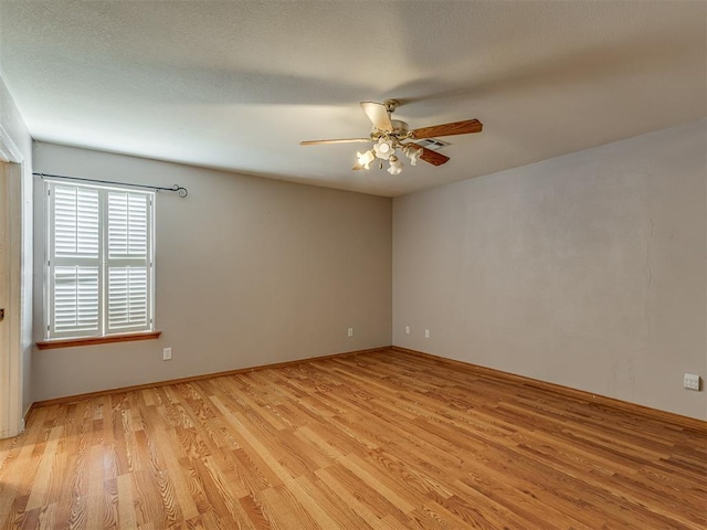 unfurnished room featuring visible vents, light wood-type flooring, a ceiling fan, and baseboards