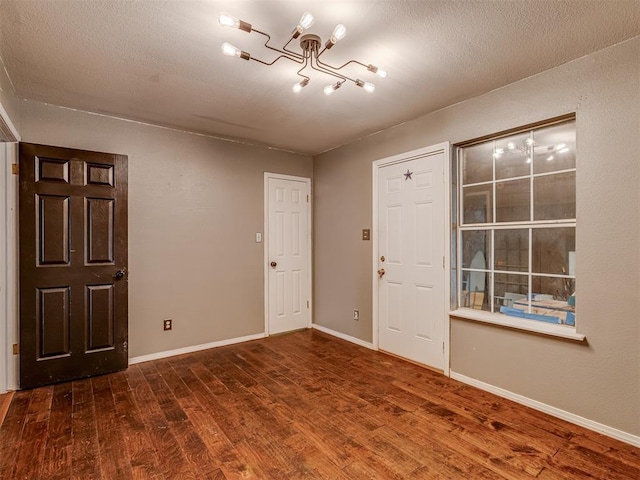 foyer entrance with a textured ceiling, wood finished floors, and baseboards