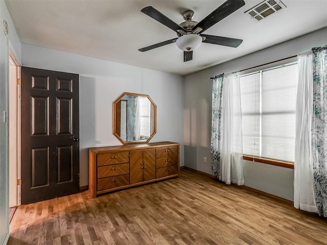 unfurnished bedroom with baseboards, ceiling fan, visible vents, and wood finished floors