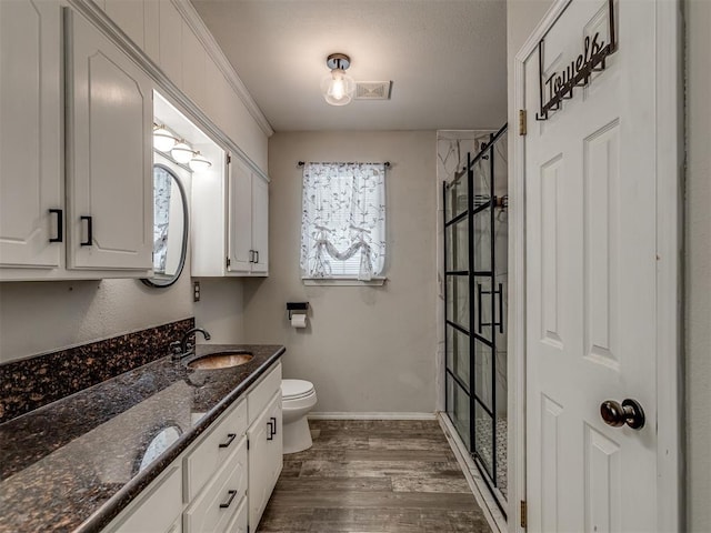 full bathroom featuring toilet, wood finished floors, vanity, baseboards, and a stall shower