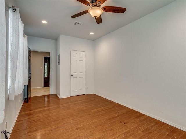 spare room featuring light wood finished floors, ceiling fan, visible vents, and baseboards