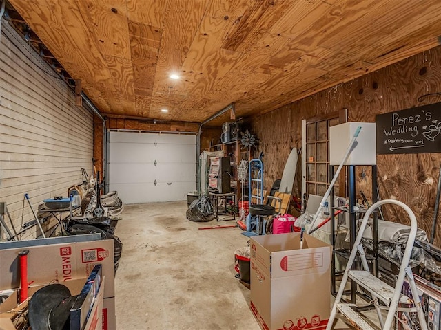 garage featuring wooden ceiling and wood walls