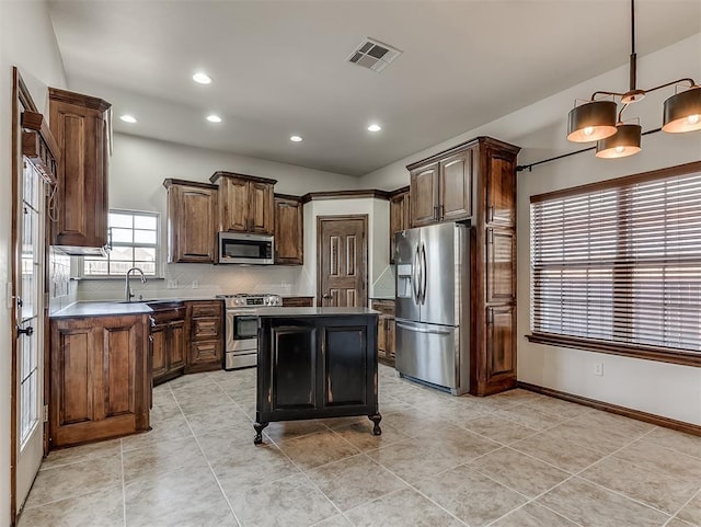 kitchen with visible vents, hanging light fixtures, backsplash, appliances with stainless steel finishes, and a kitchen island