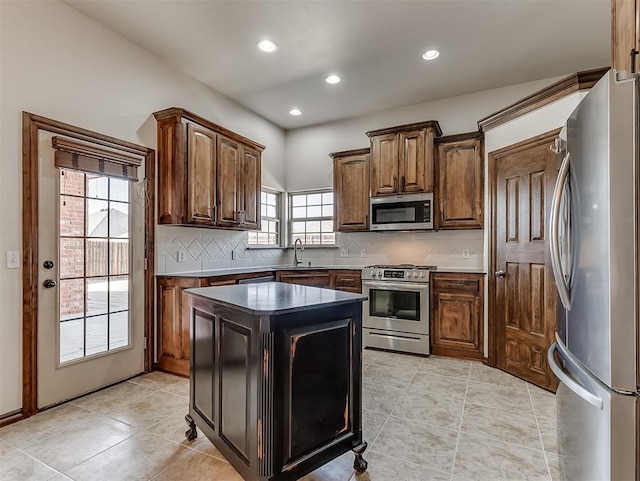 kitchen with light tile patterned floors, decorative backsplash, dark countertops, a kitchen island, and appliances with stainless steel finishes