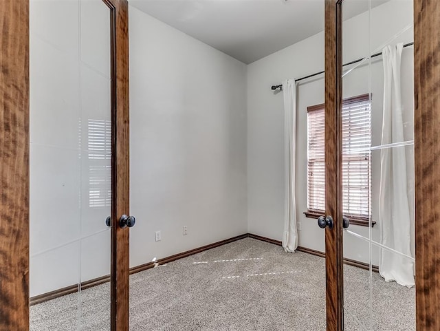 unfurnished room featuring french doors, light colored carpet, and baseboards