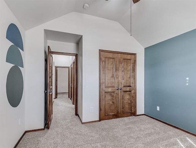 unfurnished bedroom featuring light carpet, baseboards, and lofted ceiling