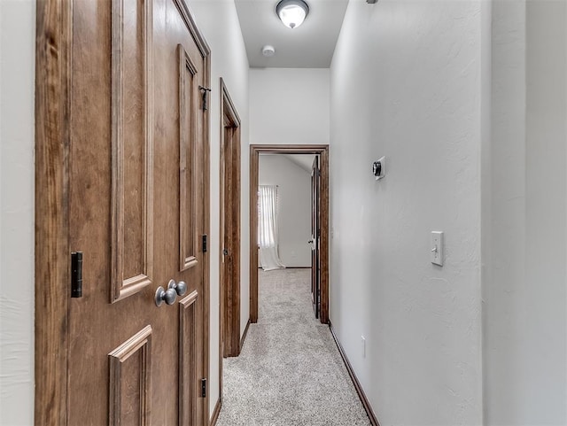 corridor featuring baseboards and light colored carpet