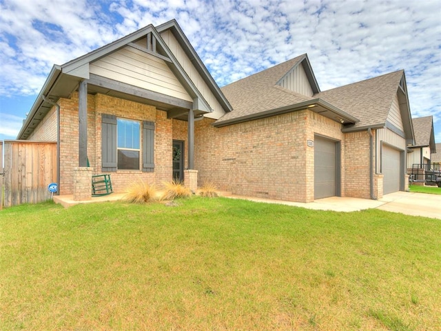 craftsman-style house featuring an attached garage, fence, a front lawn, and brick siding