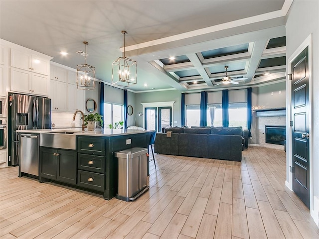 kitchen with white cabinets, stainless steel appliances, a glass covered fireplace, and open floor plan