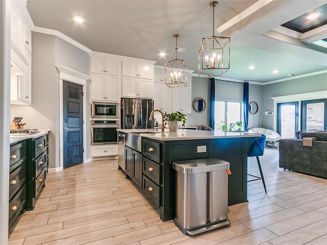 kitchen featuring stainless steel appliances, wood finish floors, white cabinets, open floor plan, and a kitchen bar